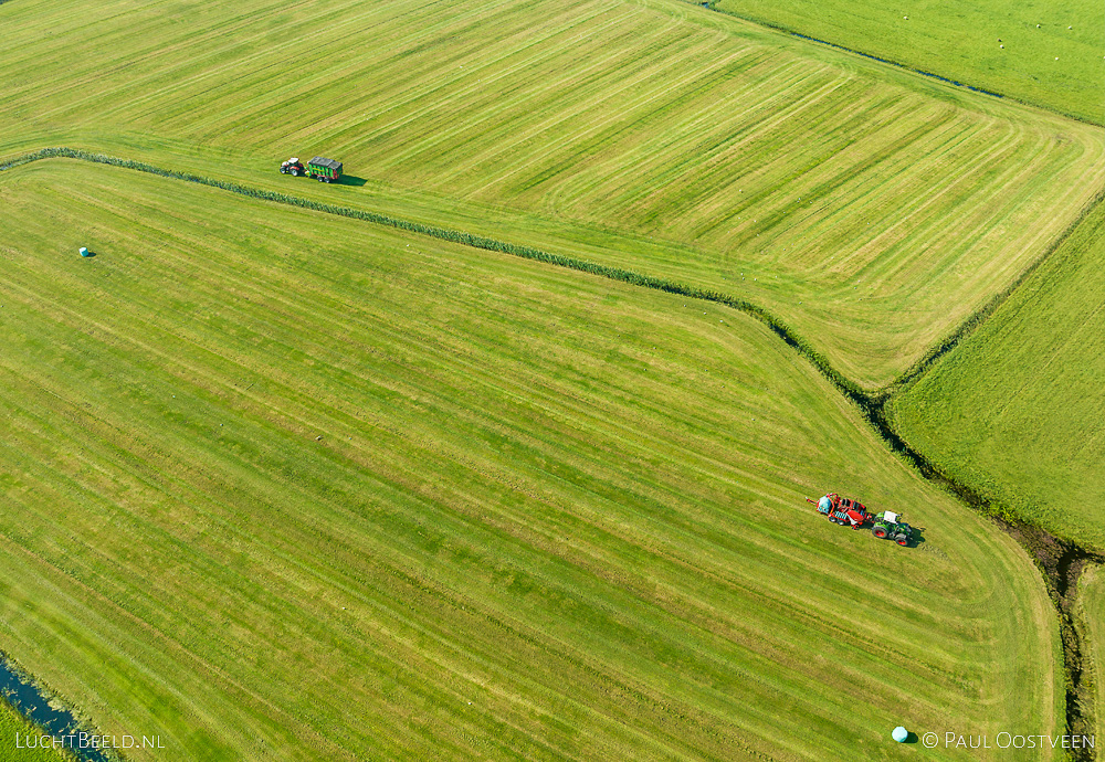 Luchtfoto van tractoren die hooi verzamelen op weilanden in Noord-Holland