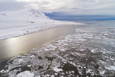 Ice and snow in winter in Borgarfjördur fjord with mountain. Aerial photo captured with a camera drone by Paul Oostveen.