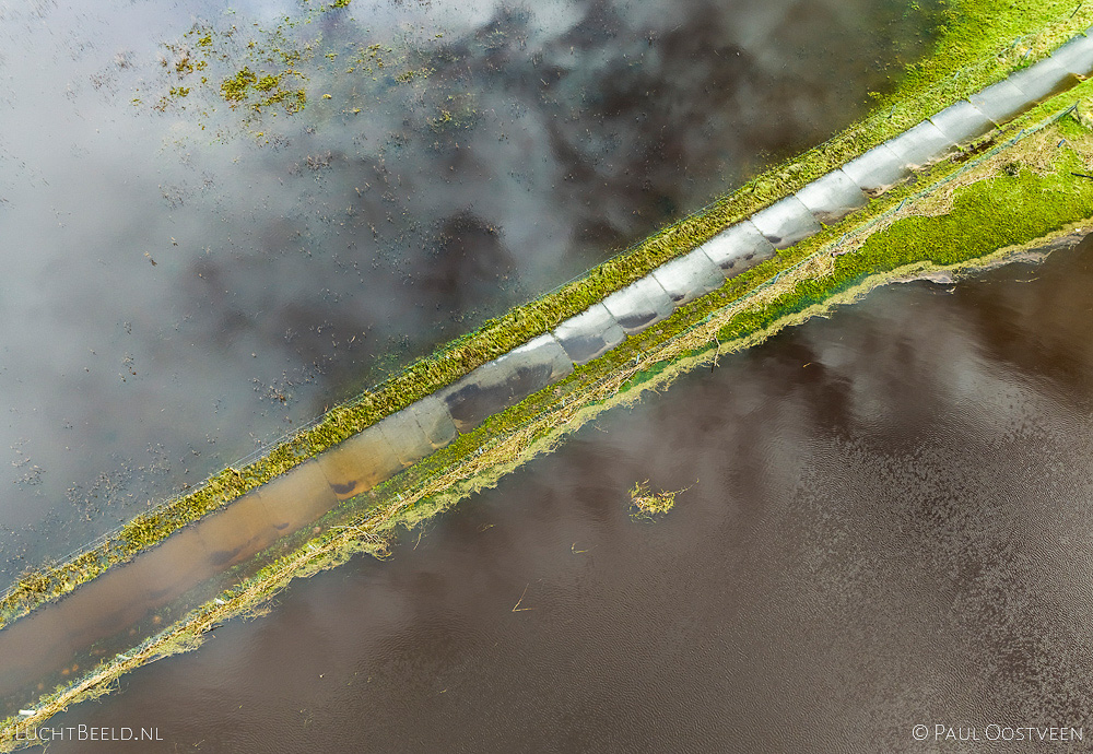 Overstroomd fietspad met reflectie van de lucht tijdens hoogwater in de Vecht
